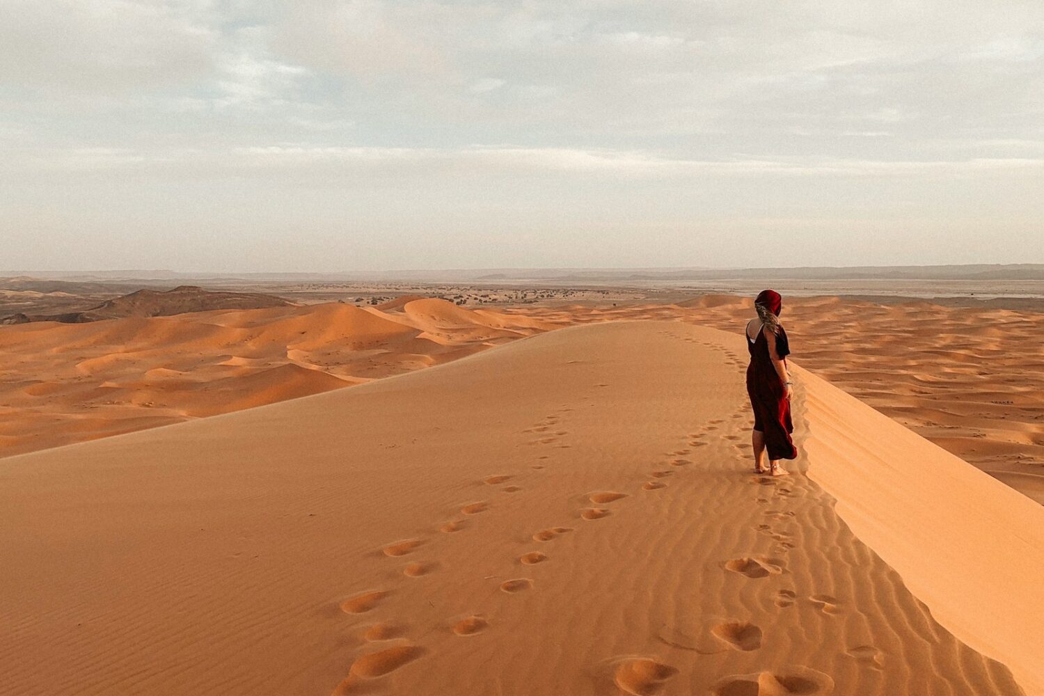 man in black jacket walking on desert during daytime