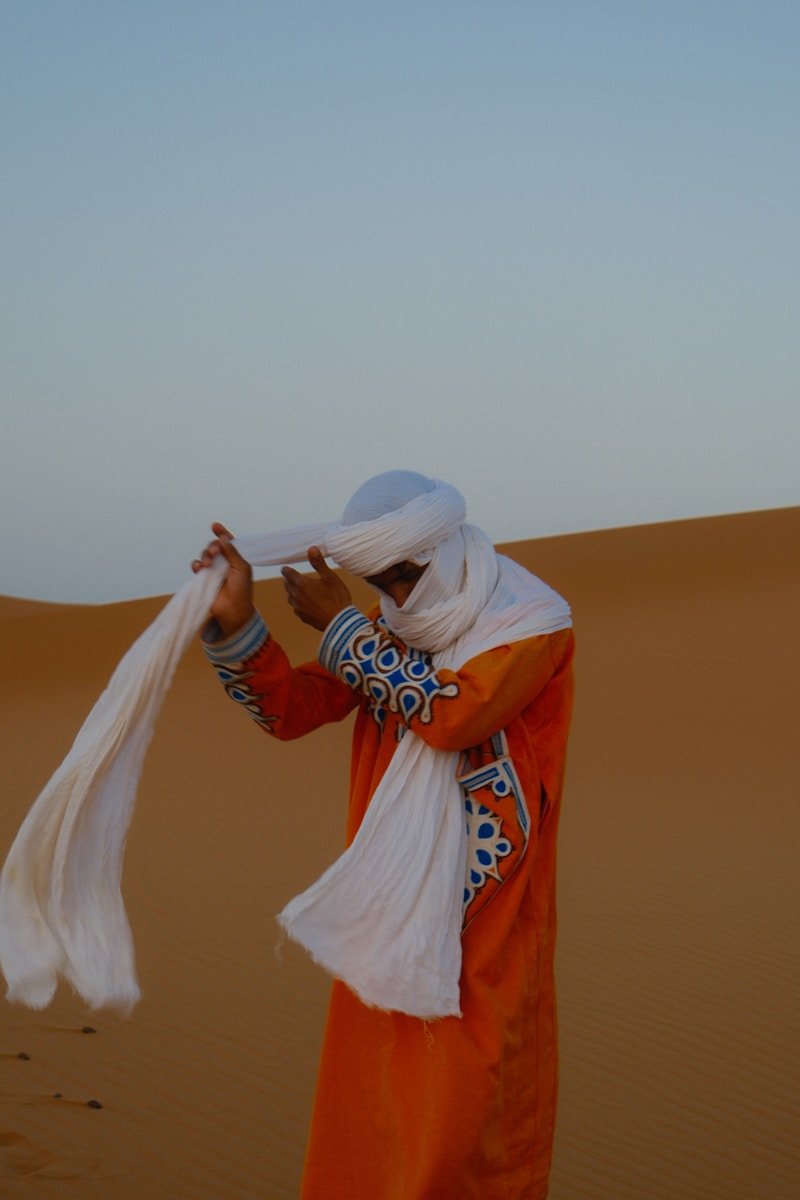 Man in traditional desert attire adjusting his turban morocco itinerary