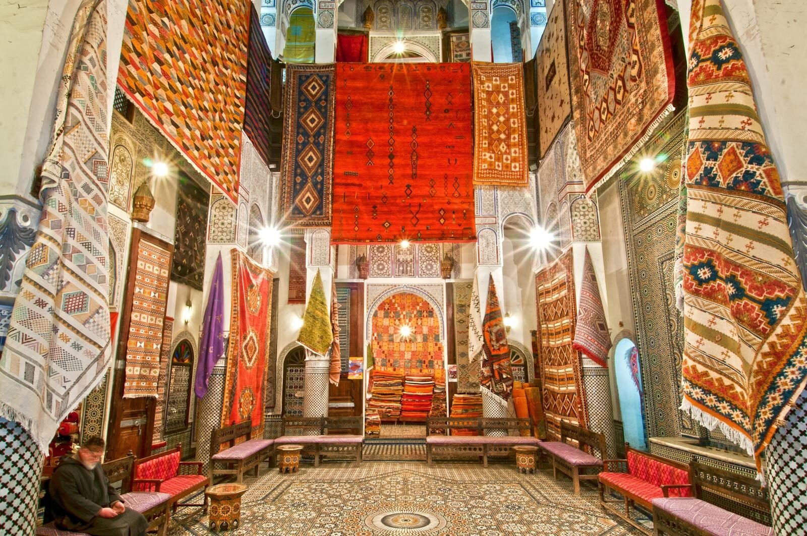 Stunning display of traditional Moroccan carpets in a Fès shop, showcasing vivid colors and intricate patterns. tours from fes